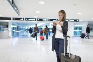 Young female passenger at the airport, using her tablet computer
